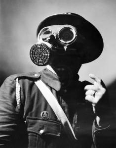 An_Air_Raid_Warden_wearing_his_steel_helmet_and_duty_gas_mask_during_the_Second_World_War._D4054